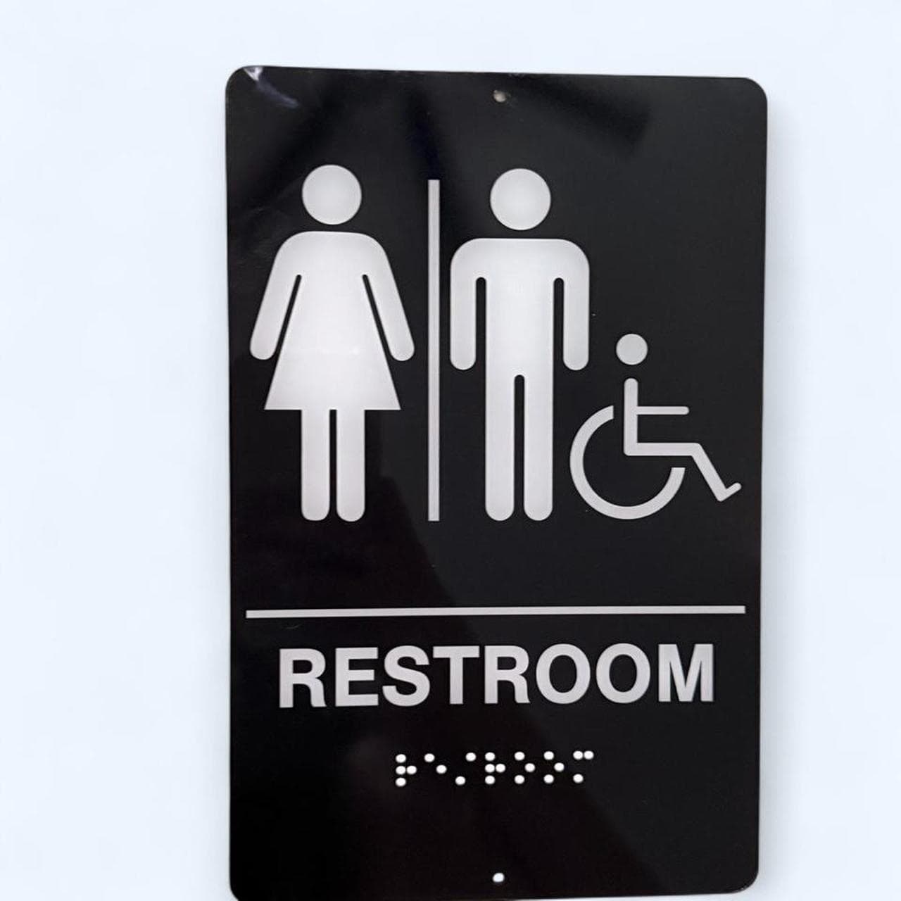 Black & white ADA restroom sign with braille — never used